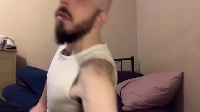 Hairy skinny man with bald blue eyes and uncut penis strips down on bed